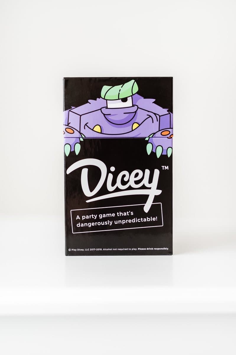 The black Dicey box on a white studio sweep, the purple monster peering over the top edge